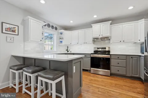 a kitchen with stainless steel appliances kitchen island granite countertop a table chairs sink and cabinets