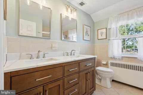 a bathroom with a granite countertop sink a toilet and a window