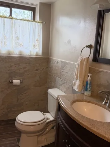 a bathroom with a granite countertop sink a toilet and a mirror