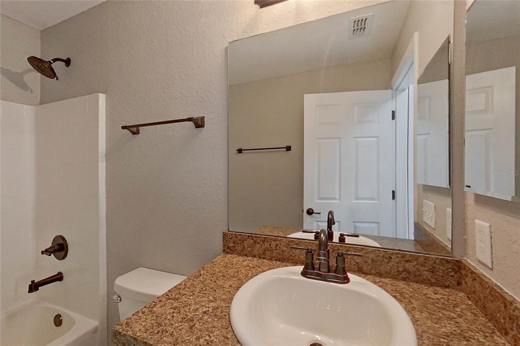 8806 Southwest 135th Street Road Ocala, FL 34473 - Photo 11 of 20 a bathroom with a granite countertop sink a mirror and shower