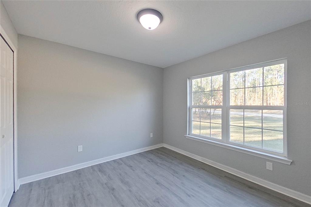 8806 Southwest 135th Street Road Ocala, FL 34473 - Photo 12 of 20 an empty room with wooden floor and windows