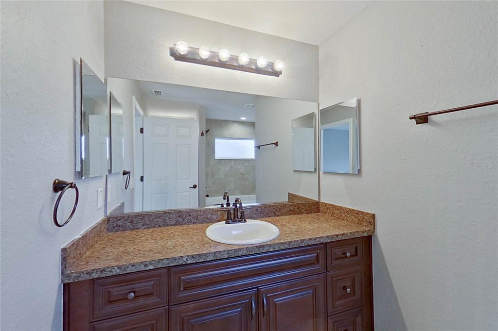 8806 Southwest 135th Street Road Ocala, FL 34473 - Photo 16 of 20 a bathroom with a granite countertop sink a mirror and shower