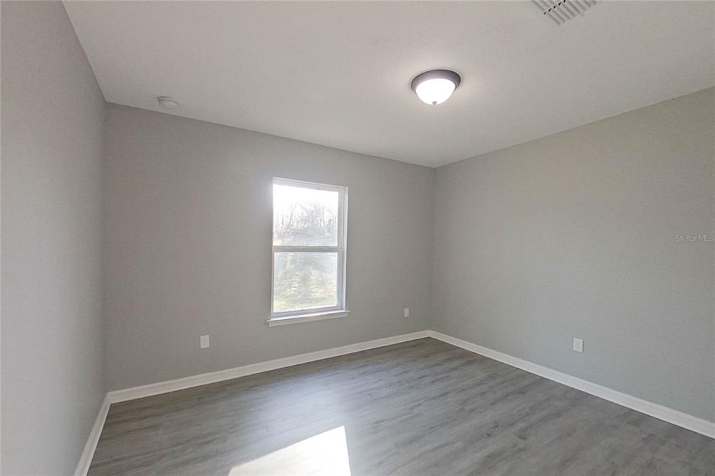 8806 Southwest 135th Street Road Ocala, FL 34473 - Photo 9 of 20 an empty room with wooden floor and windows