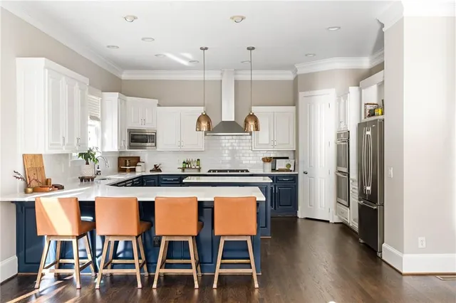 a kitchen with stainless steel appliances granite countertop a table chairs stove and white cabinets