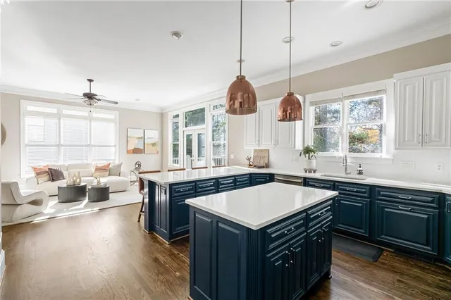 a kitchen with a stove a sink dishwasher a couches and chairs with wooden floor