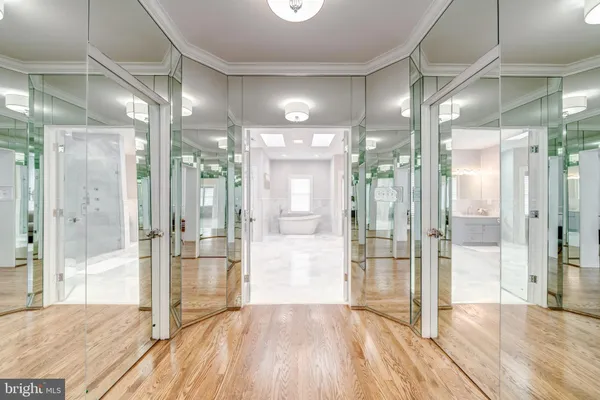 a view of a hallway with wooden floor and a glass door shower