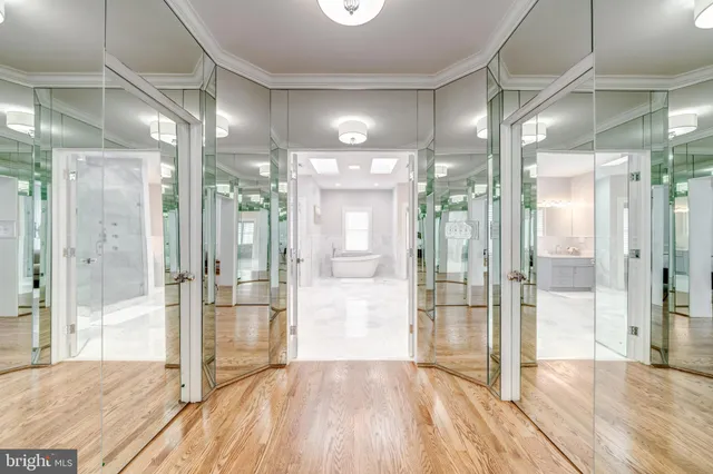 a view of a hallway with wooden floor and a glass door shower