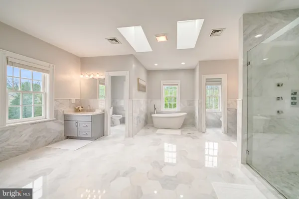 a spacious bathroom with a bathtub shower sink mirror and toilet