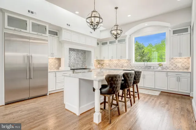 a kitchen with stainless steel appliances granite countertop a table chairs refrigerator and microwave