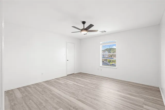 an empty room with a ceiling fan and wooden floor
