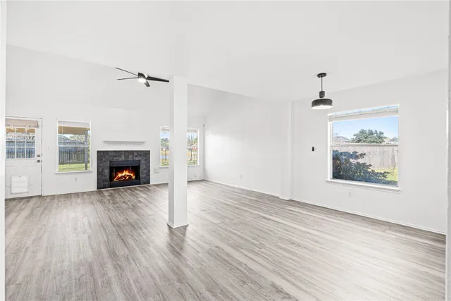 an empty room with wooden floor a fireplace and windows