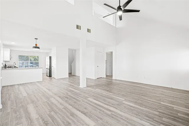 a view of an empty room with wooden floor and a kitchen