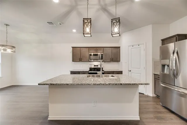 a kitchen with stainless steel appliances granite countertop a sink cabinets and wooden floor