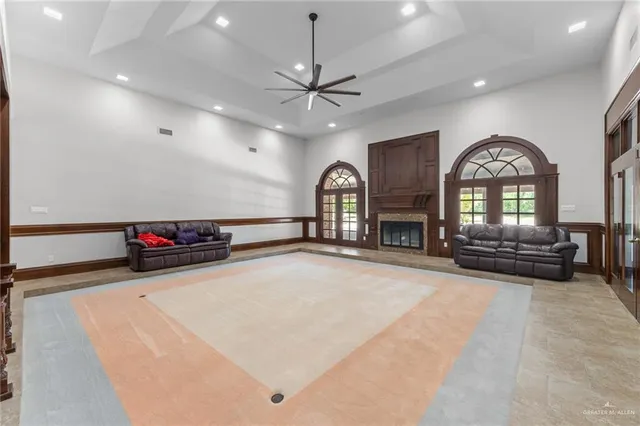 a view of a livingroom with a fireplace a ceiling fan and wooden floor