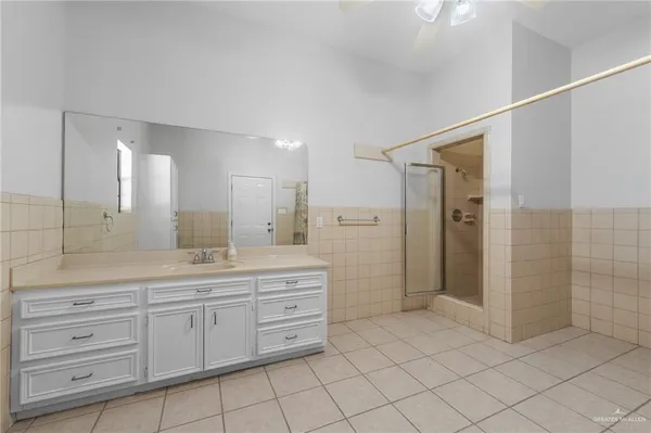 a spacious bathroom with a shower a sink and a mirror