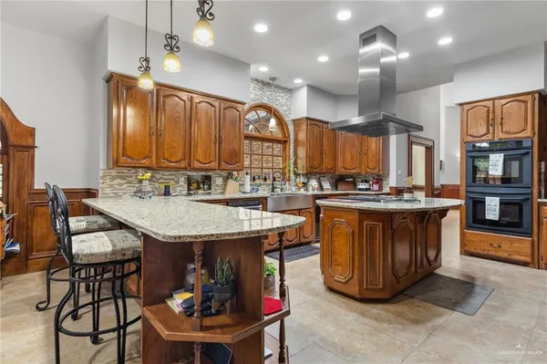 a kitchen with stainless steel appliances granite countertop a table chairs and a refrigerator