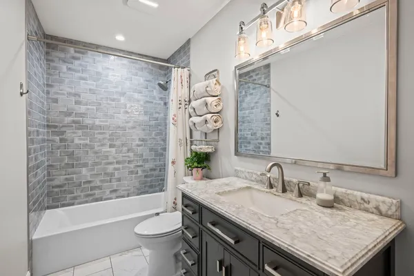 a bathroom with a granite countertop sink a toilet a mirror and bathtub