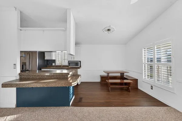 a kitchen with kitchen island granite countertop a stove top oven a sink a dining table and chairs