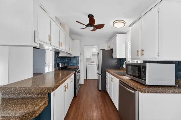 a kitchen with stainless steel appliances granite countertop a refrigerator a stove a sink and white cabinets