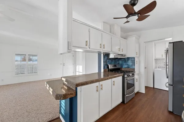 a kitchen with stainless steel appliances granite countertop a stove a refrigerator a sink and white cabinets