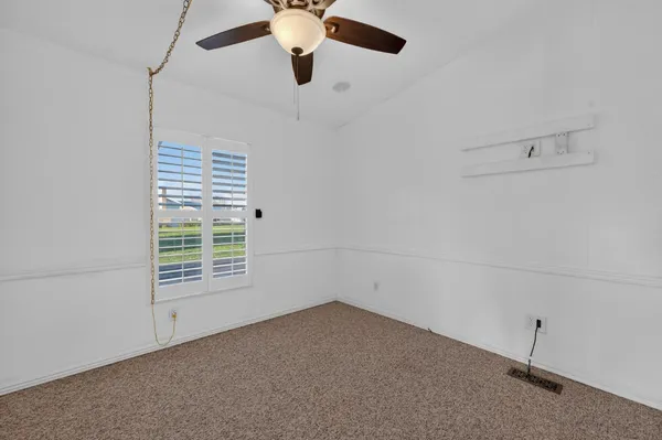 an empty room with a window and a ceiling fan