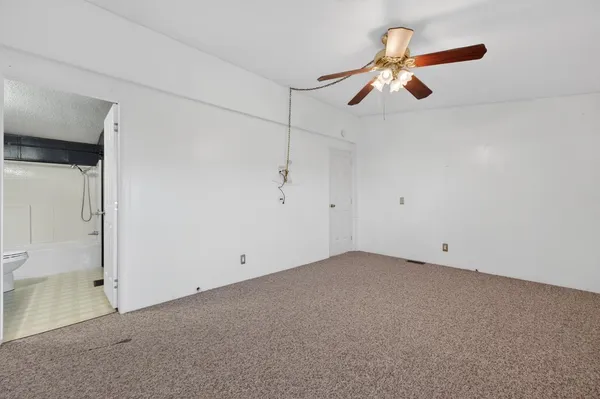 an empty room with a ceiling fan and a window