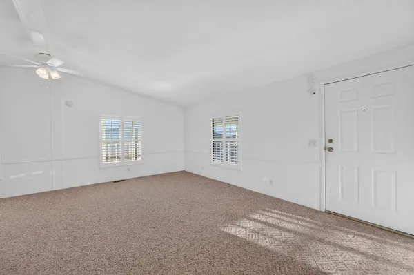 a view of a big room with windows and chandelier fan