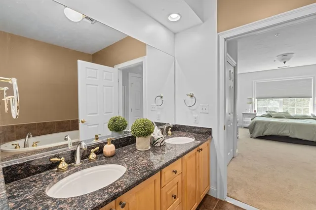 a en suite bathroom with a granite countertop double vanity and a mirror