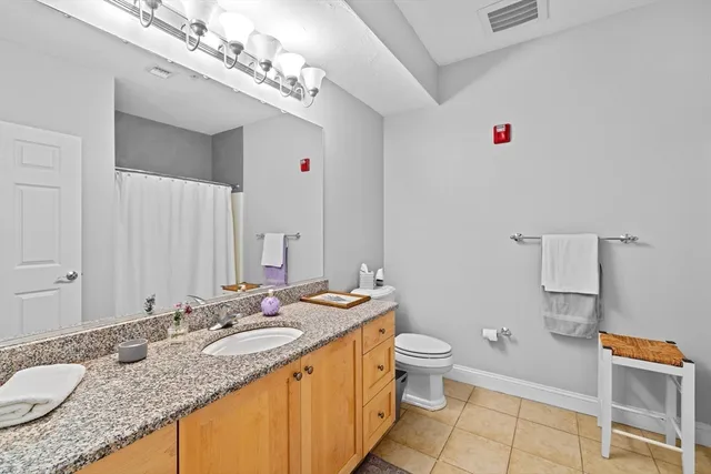 a bathroom with a granite countertop double vanity sink a mirror and a toilet