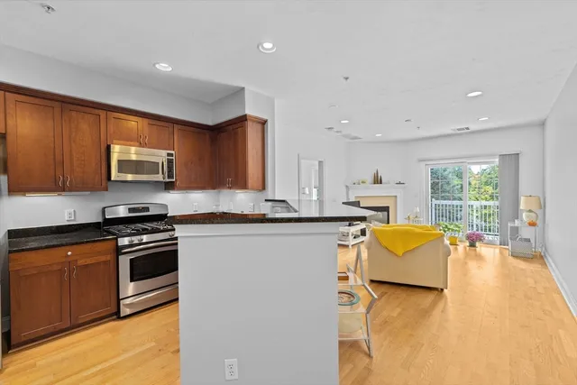 a kitchen with stainless steel appliances granite countertop a stove top oven a sink dishwasher a dining table and chairs with wooden floor