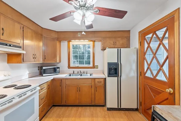 a kitchen with stainless steel appliances granite countertop a refrigerator a sink dishwasher a stove and a dining table with wooden floor