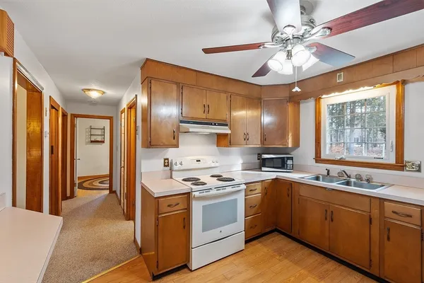 a kitchen with a sink stainless steel appliances cabinets and a large window