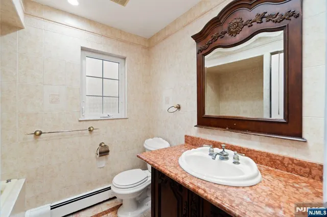 a bathroom with a granite countertop toilet sink and mirror