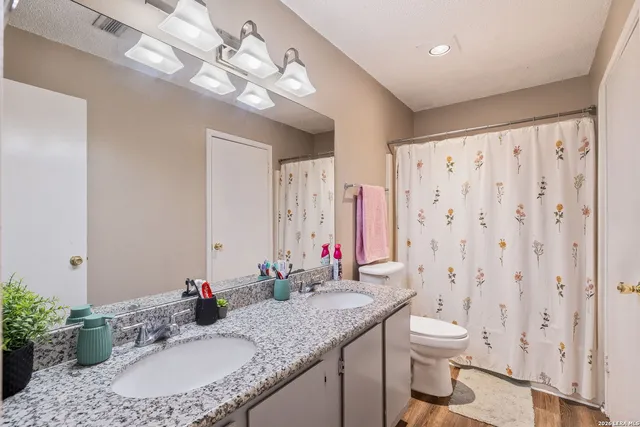 a bathroom with a granite countertop sink a toilet and a mirror