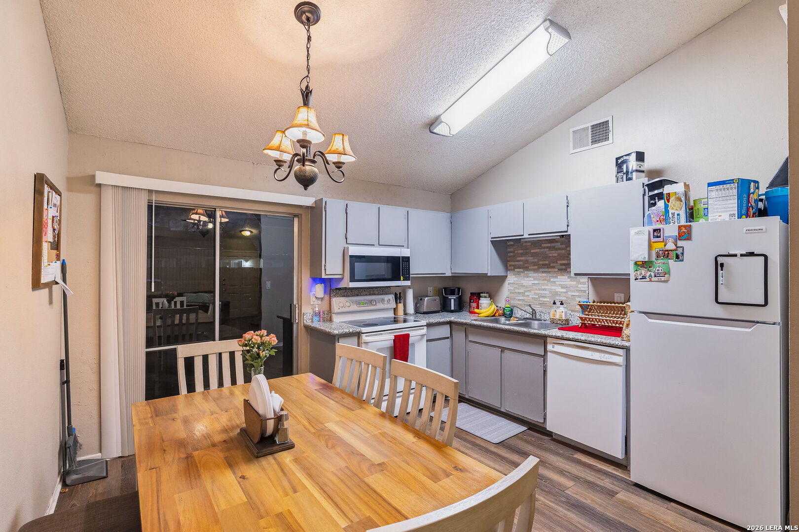 9140 Timber Path, Unit 2502 San Antonio, TX 78250 - Photo 9 of 26 a kitchen with a refrigerator a stove top oven a dining table and chairs