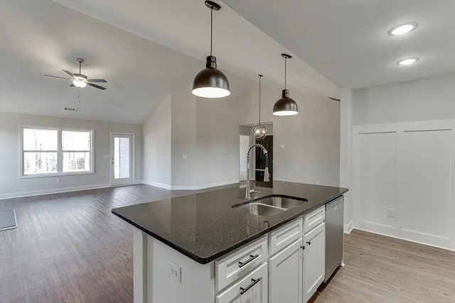 a kitchen with a sink a chandelier stainless steel appliances and wooden floor