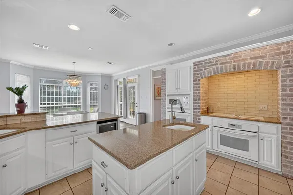 a kitchen with granite countertop a sink and white cabinets with a large window