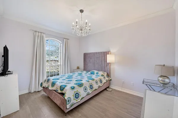 a bedroom with a bed chandelier and a window