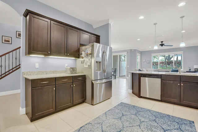 a kitchen with stainless steel appliances granite countertop a refrigerator a sink a stove with wooden cabinets