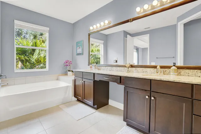 a bathroom with a granite countertop bathtub a sink and a window