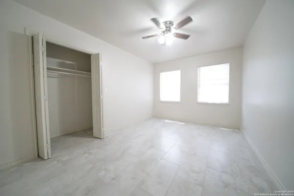 an empty room with windows and chandelier fan