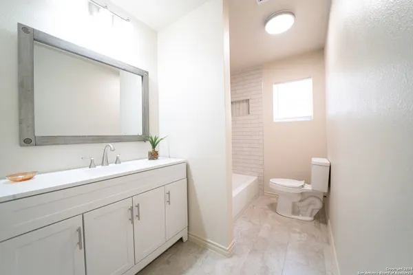 a bathroom with a toilet a sink a mirror and vanity