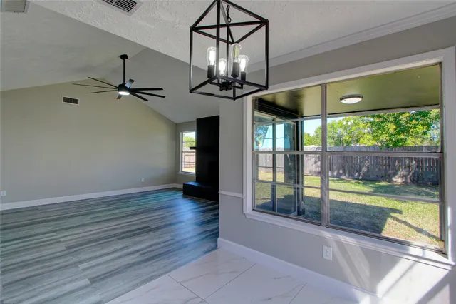 a view of a room with wooden floor a ceiling fan and a fireplace