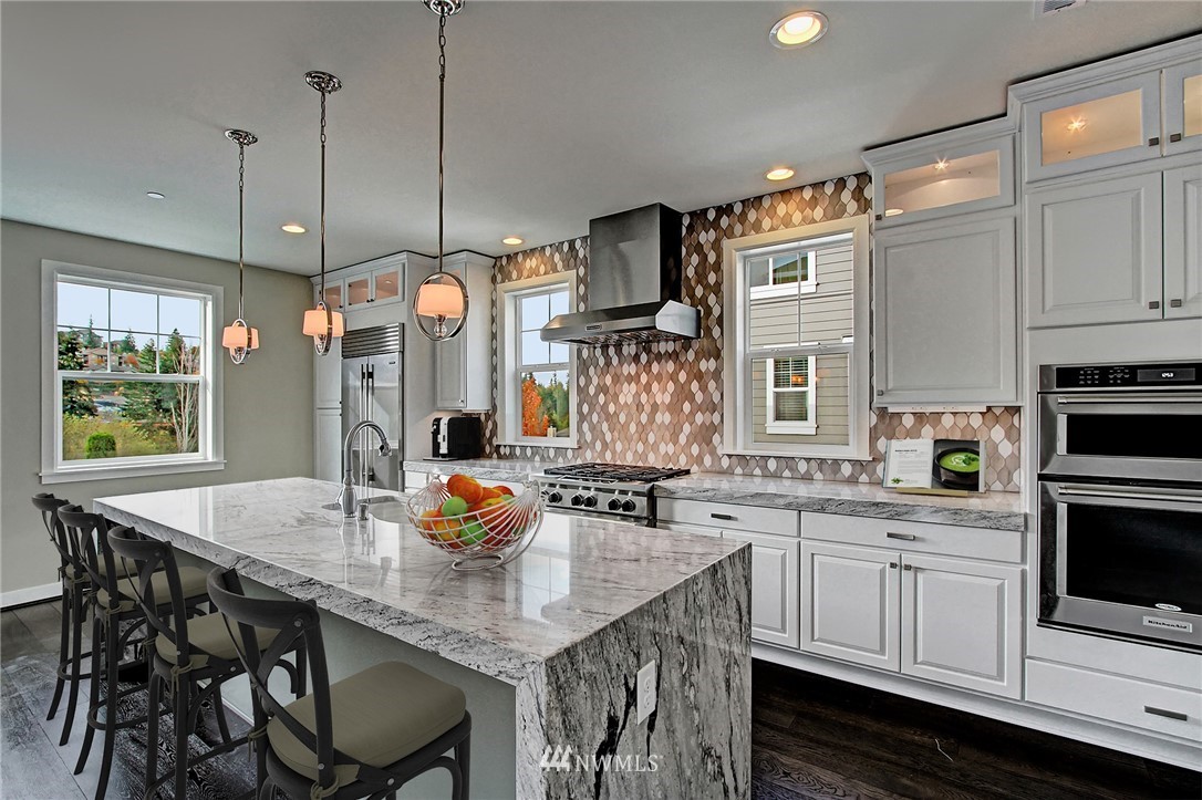 26542 Northeast Big Rock Road, Unit 101 Duvall, WA 98019 - Photo 4 of 19 a kitchen with stainless steel appliances granite countertop a sink a stove a dining table chairs and fireplace