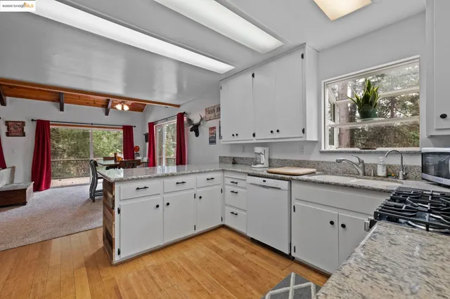 a kitchen with sink stove and white cabinets with wooden floor