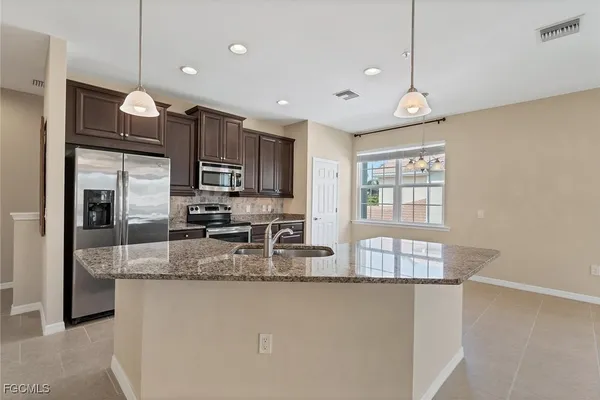 a kitchen with stainless steel appliances granite countertop a sink a stove and a refrigerator