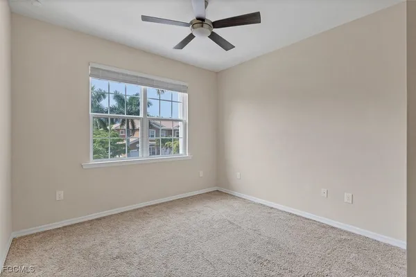 an empty room with a window and a fan