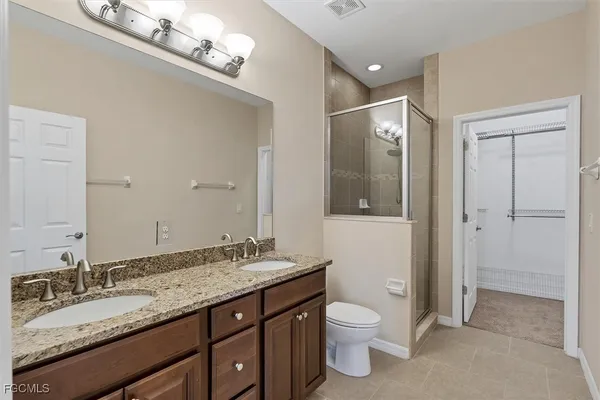 a bathroom with a granite countertop double vanity and a mirror