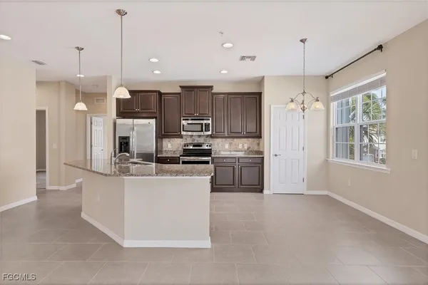 a kitchen with stainless steel appliances kitchen island a sink a refrigerator and a cabinets