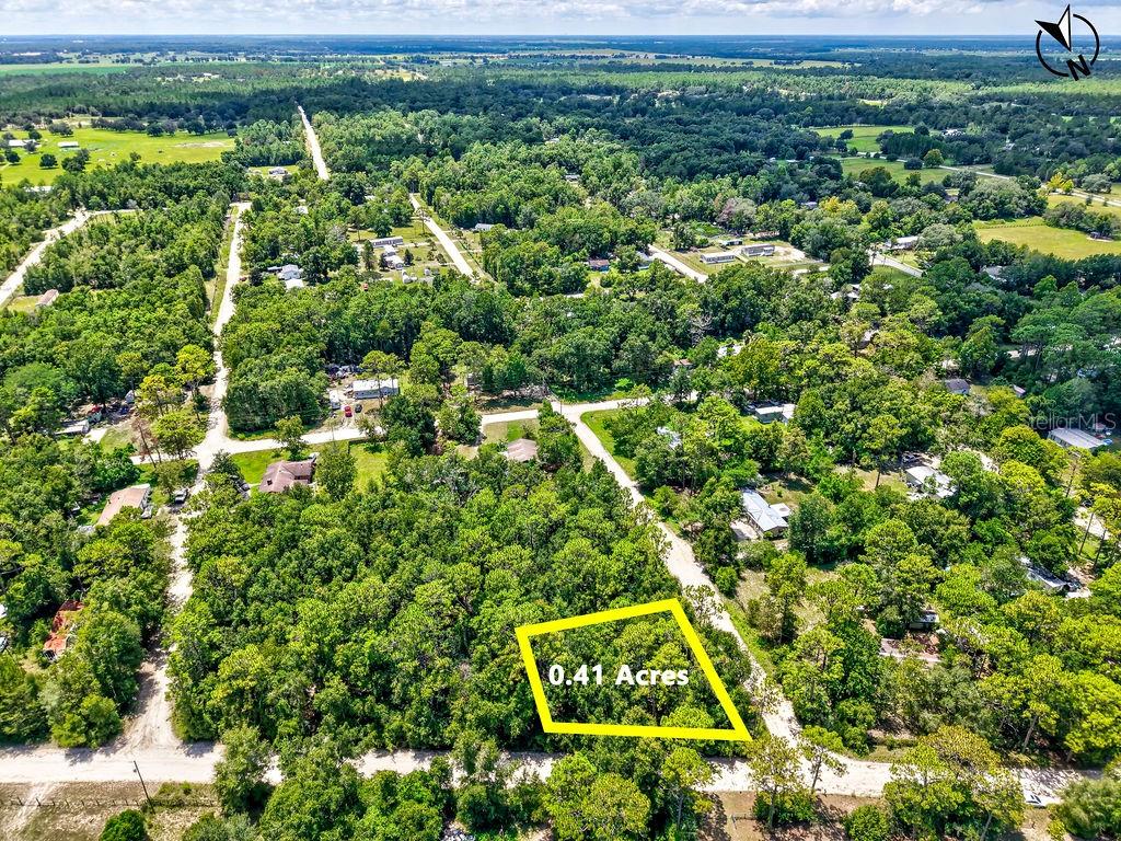 an aerial view of residential houses with outdoor space and trees